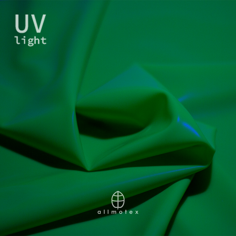 Close-up of green glossy latex reacting to UV light with Allmotex logo.